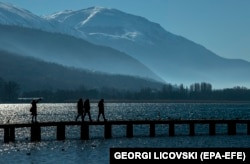 People walking over a wooden bridge at Lake Ohrid