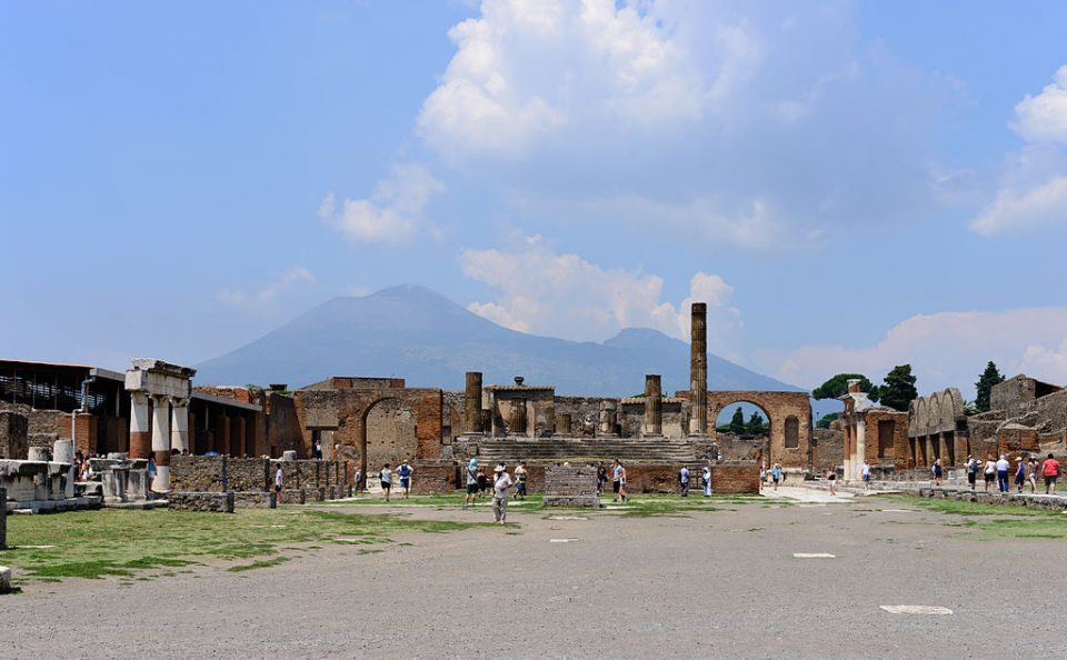 Tourists explore the ancient Roman city of Pompeii with Vesuvius in the backdrop.