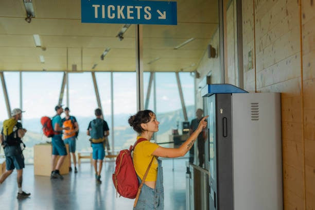 Woman using smartphone to buy tickets in machine for cable car