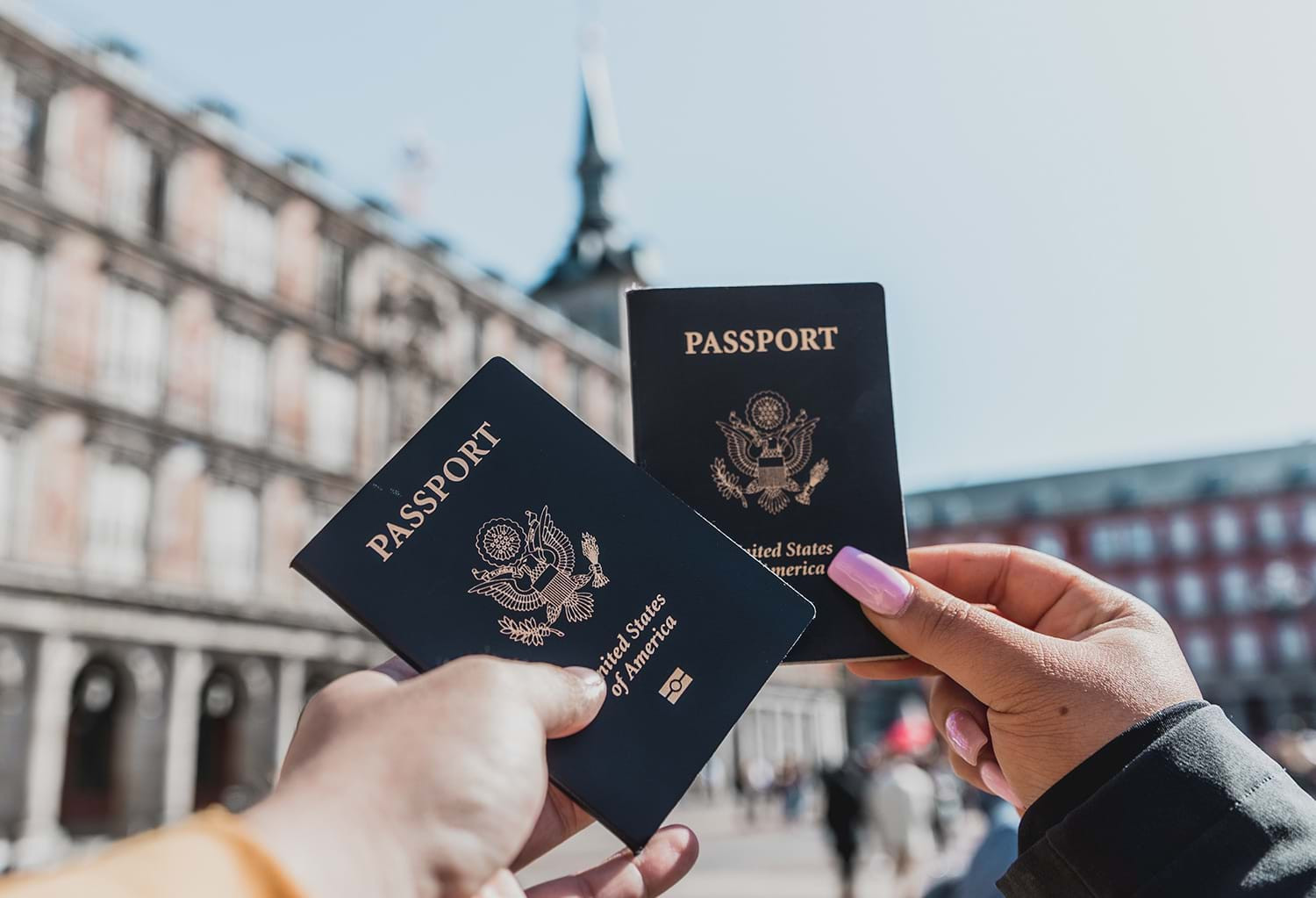 Two people holding passports in city courtyard, ready for a safe journey