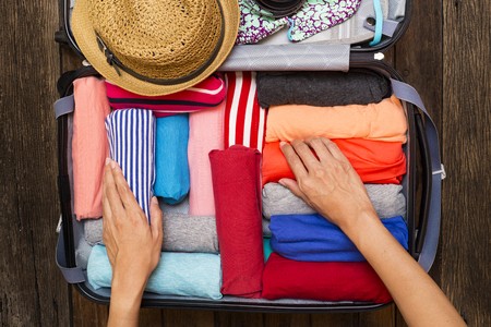 woman rolling her clothing in a suitcase for a trip
