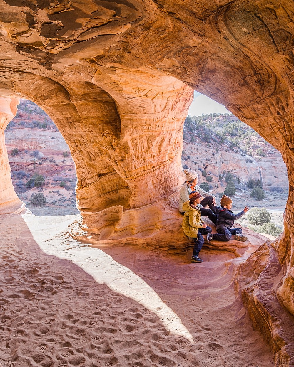 Family scaling sandstone at Moqui Caverns, showcasing a challenging but rewarding hike during a Spring Break adventure in 2021
