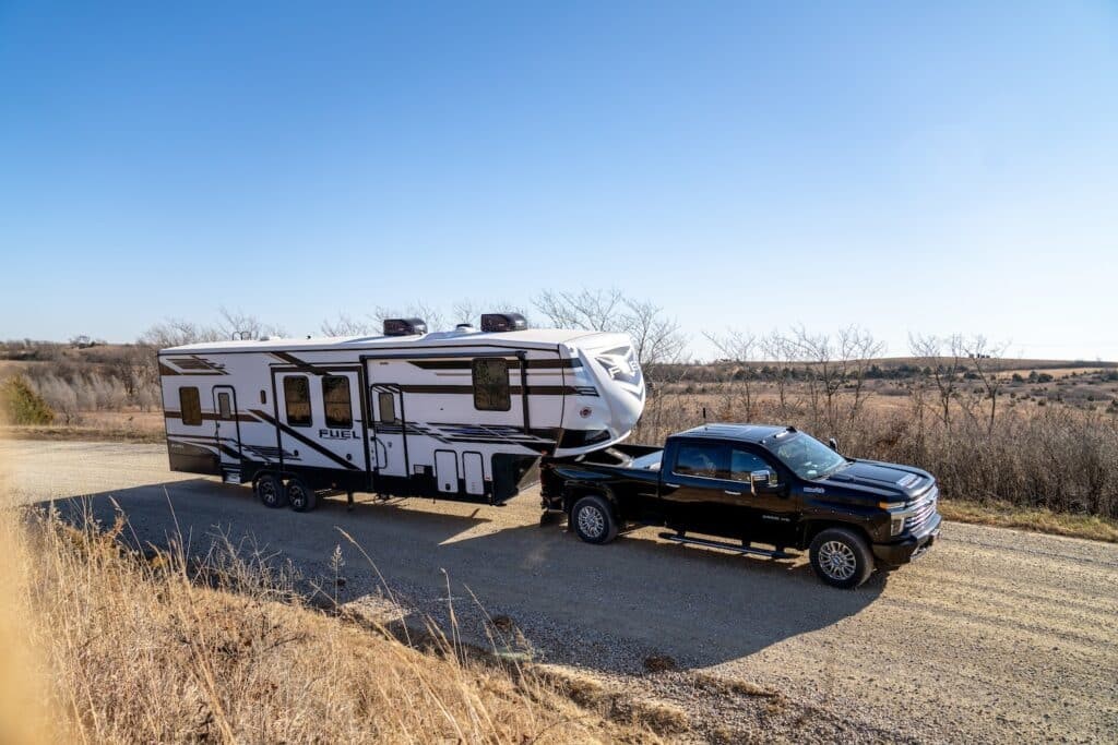heartland fifth wheel toy hauler pulled by a truck on gravel road.
