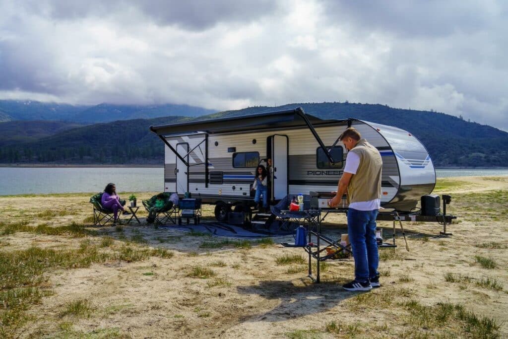 Heartland Pioneer set up on a lakefront beach, with campers cooking