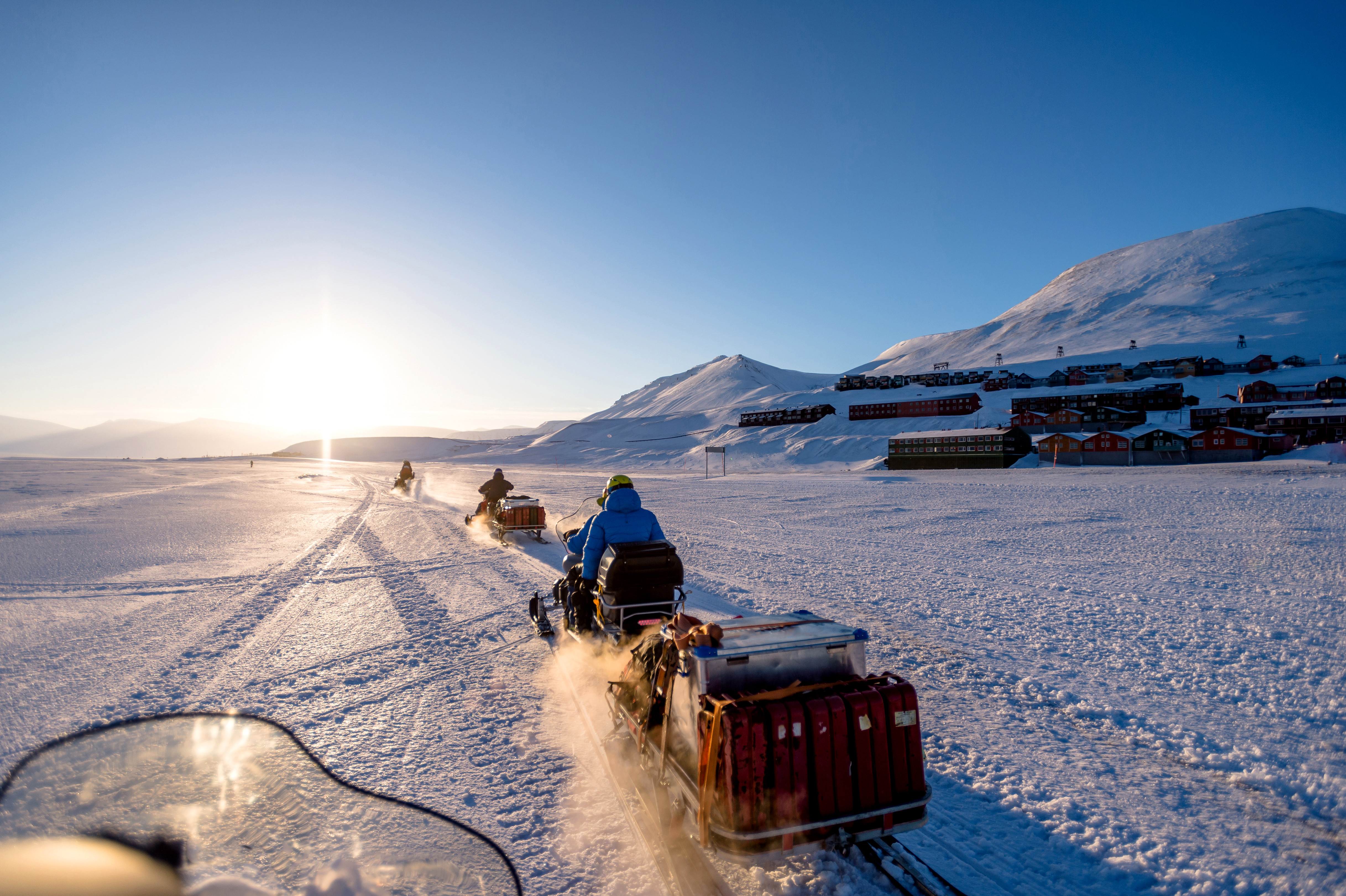 Snowmobiles traversing the icy landscape near Longyearbyen, Svalbard, under a clear sky