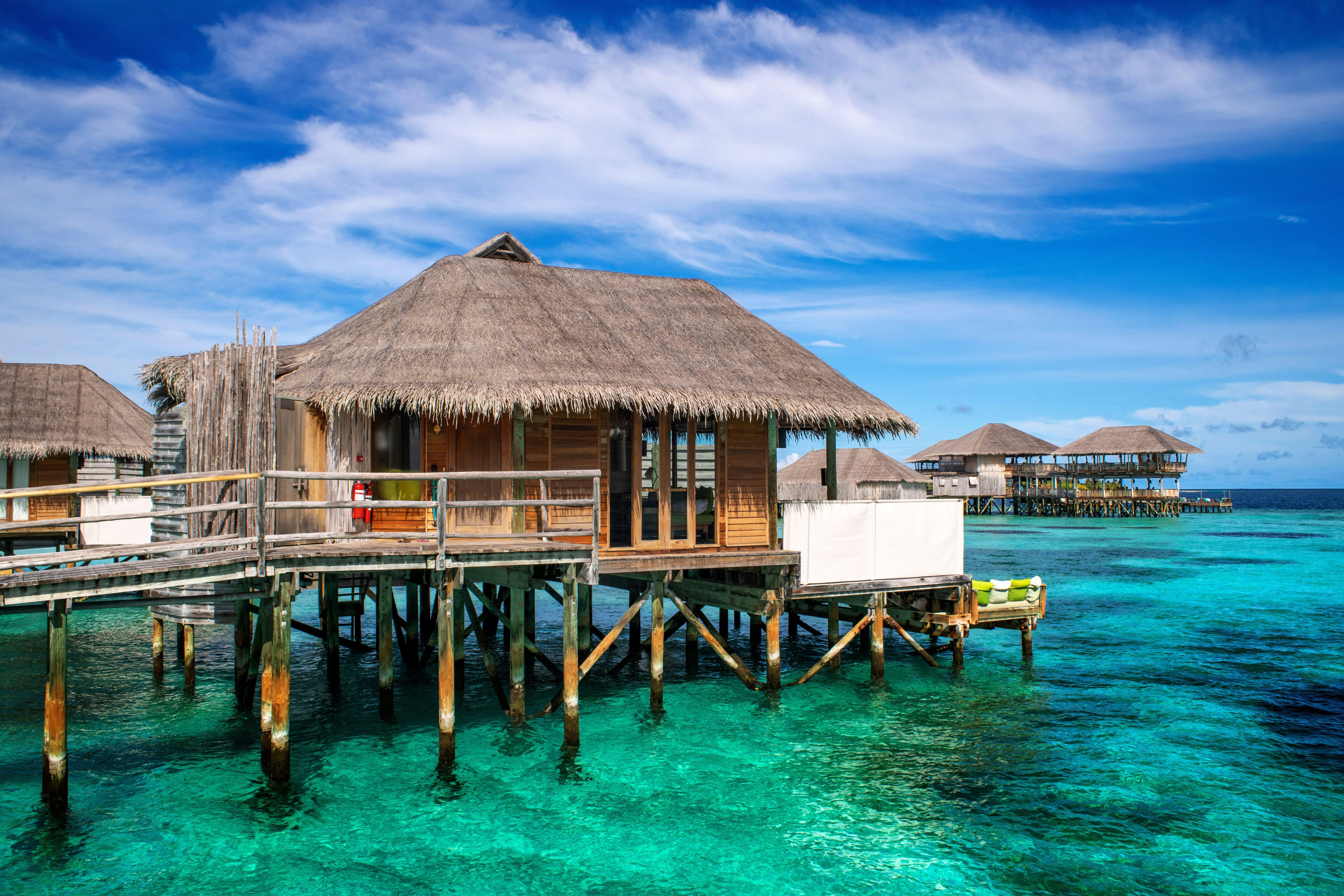 Overwater villas at Six Senses Laamu in the Maldives, featuring thatched roofs and crystal-clear waters