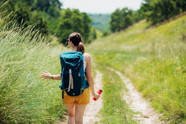 Young woman walking through the mountain paths and enjoying