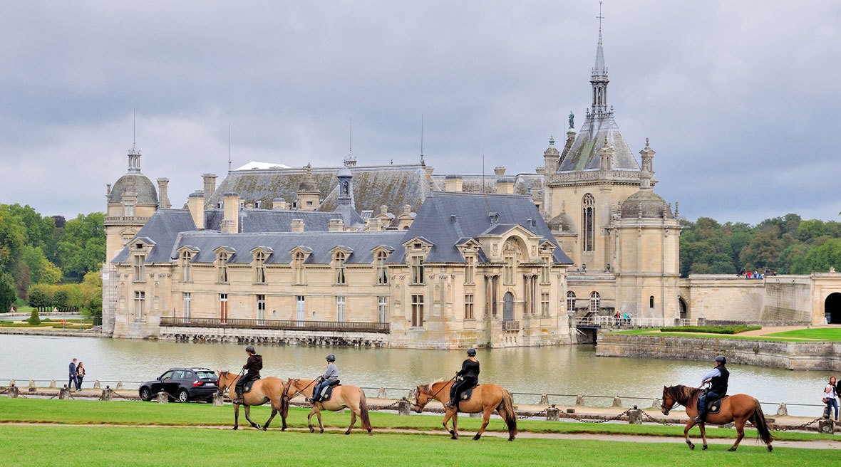 French castle next to water with horses
