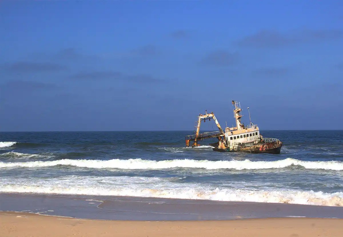 Skeleton Coast Namibia tourism attraction: Dunes meeting the ocean in a fog-shrouded landscape.