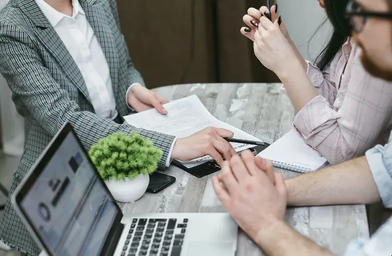 Réunion professionnelle avec ordinateur portable, documents et mains lors d