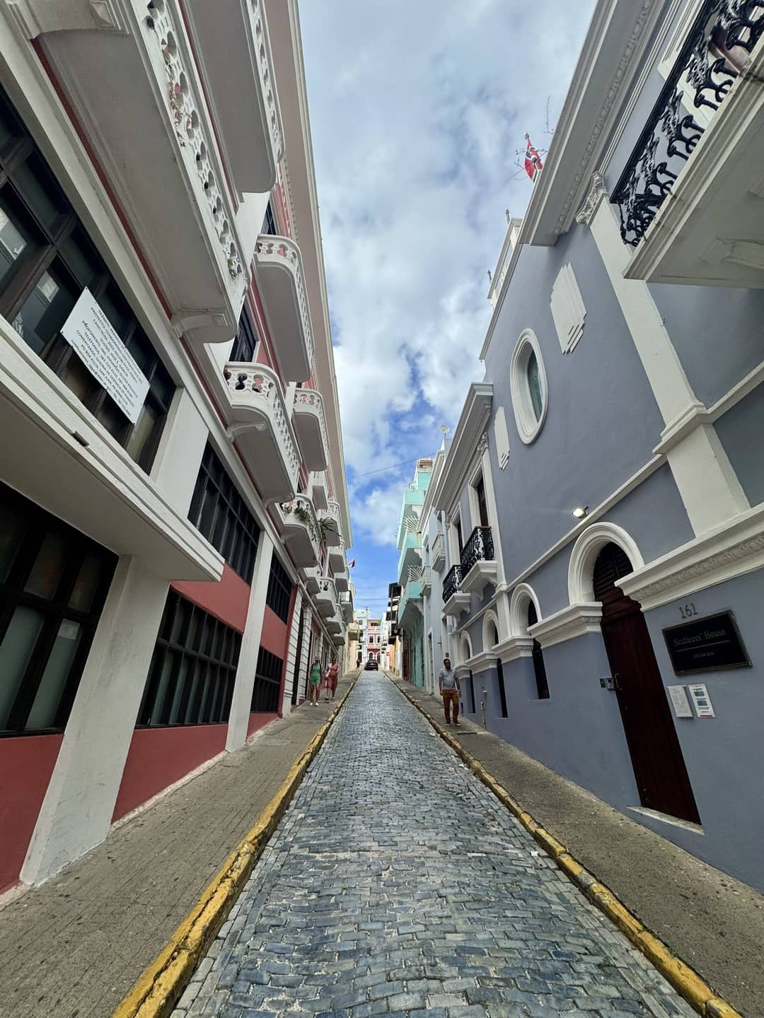 A charming cobblestone street in a city, featuring shops and cafes, with pedestrians strolling along the pathway.