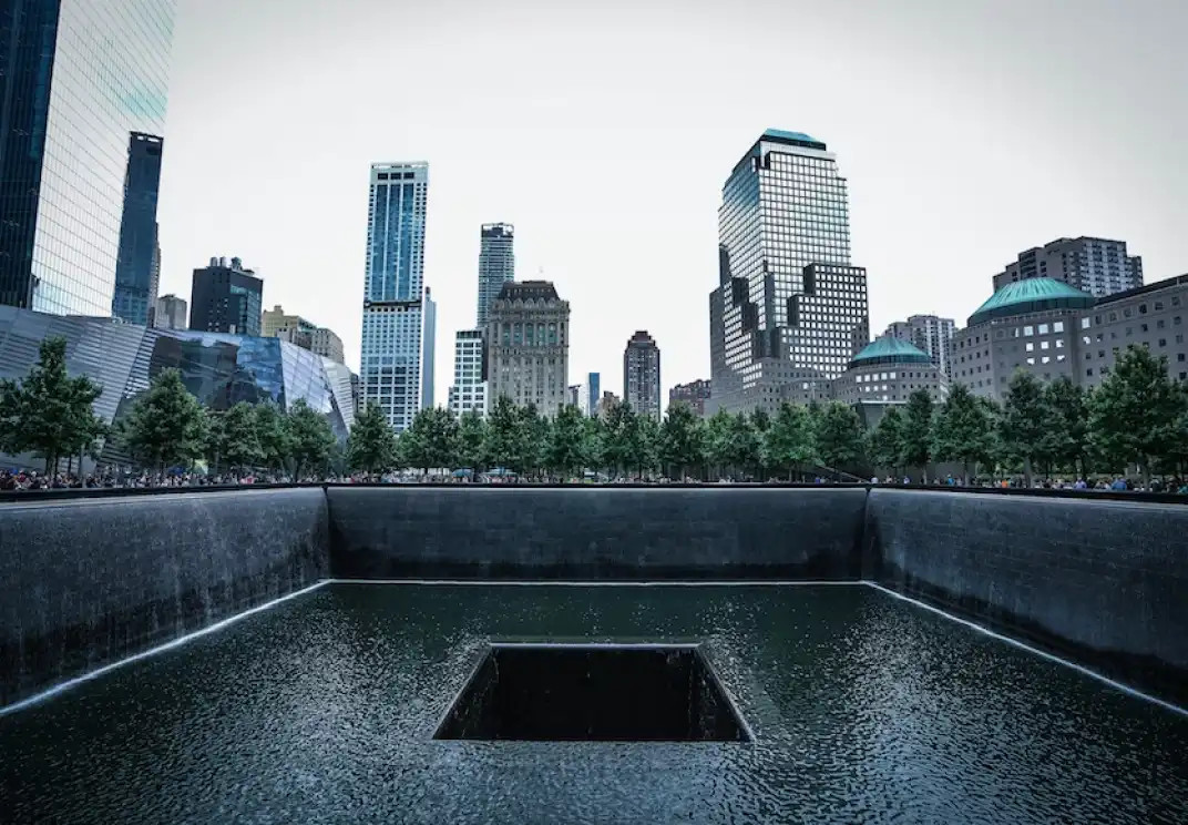 9/11 Memorial reflecting pool with New York City skyline in background