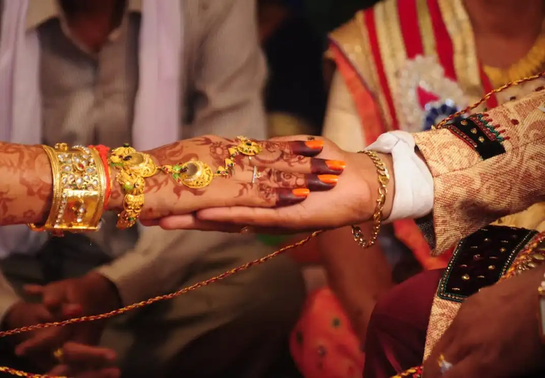 Hands with mehndi and gold jewelry during traditional wedding ceremony