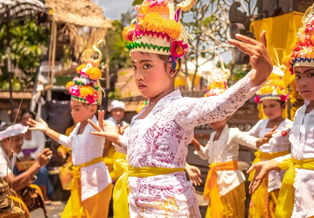Young Balinese dancers in traditional white and yellow costumes performing ritual