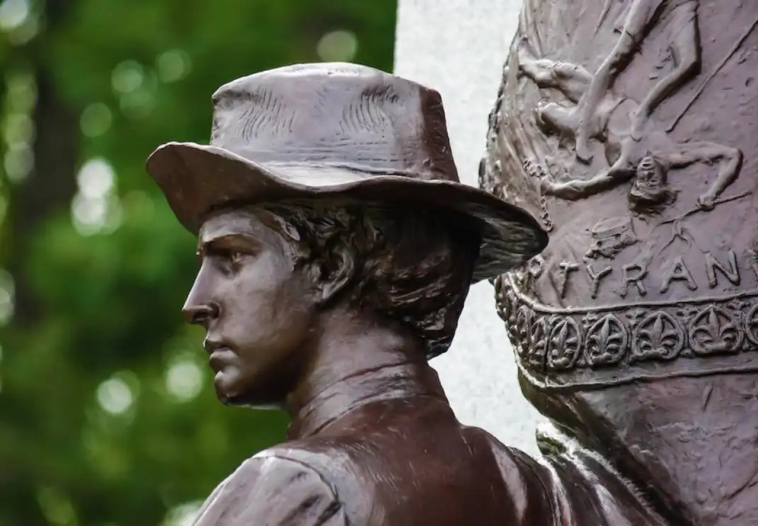 Bronze statue of a person in profile wearing a wide-brimmed hat