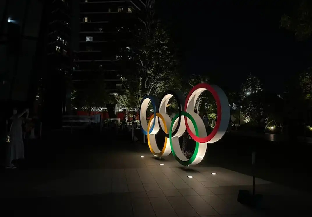 Olympic rings illuminated at night near building and trees