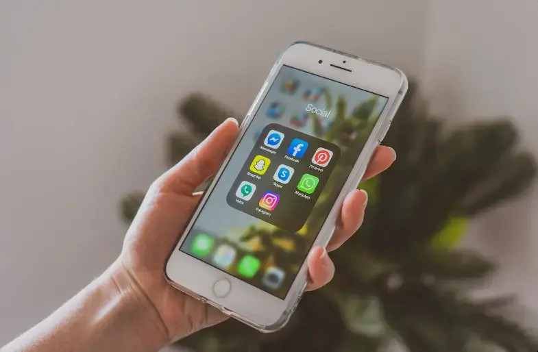 Hand holding a smartphone with social media apps