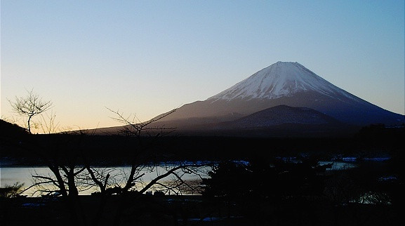 Mount Fuji towering over a serene lake, reflecting its symmetrical cone shape