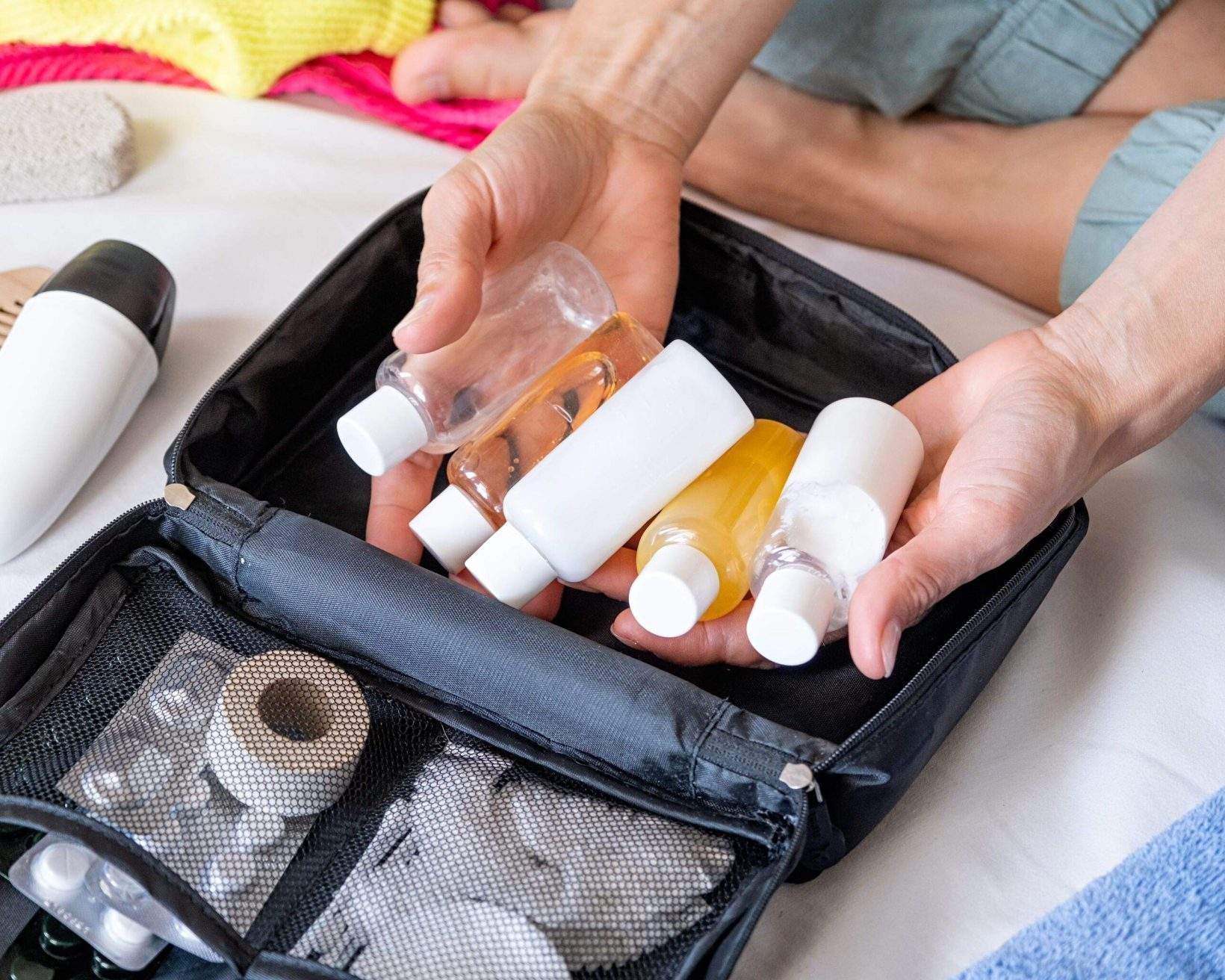 Travel cosmetics kit with bottles, pills and cosmetics on bed , top view