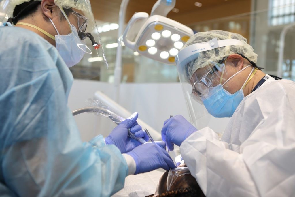 Two PDM periodontist specialists work on a patient who is undergoing treatment for periodontal disease, ensuring their gums are healthy
