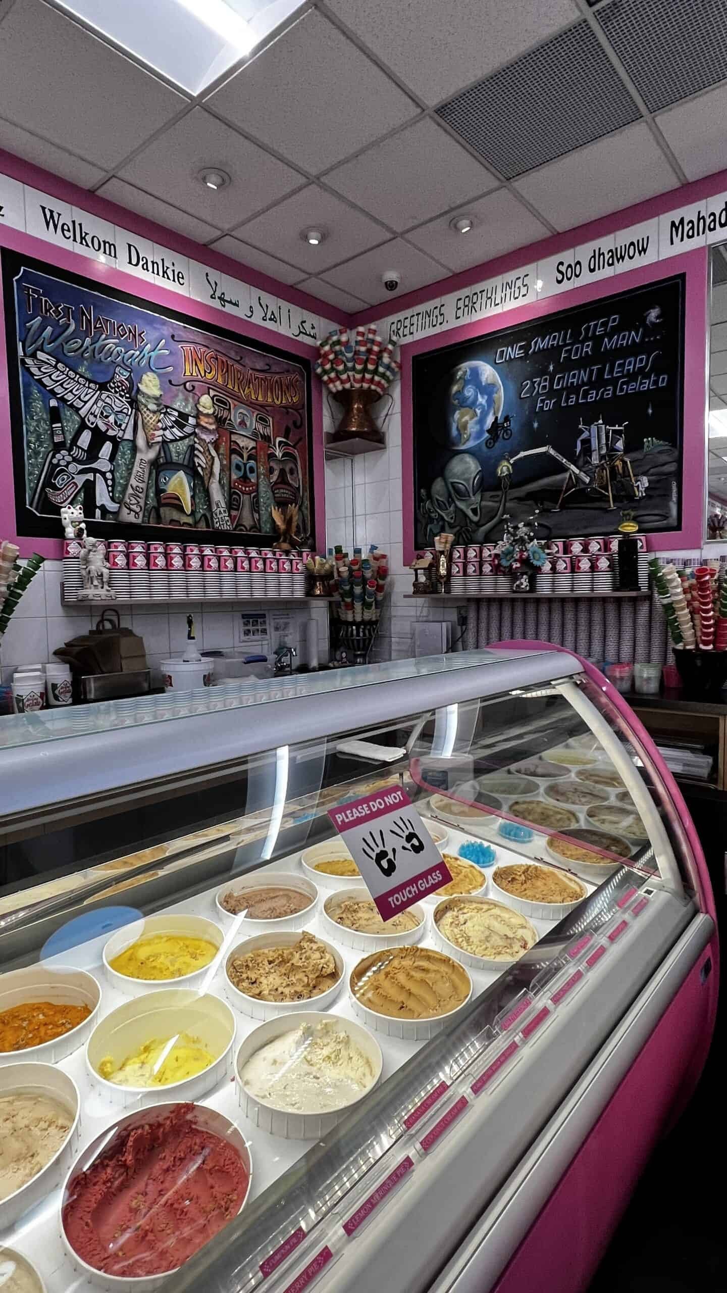 Ice cream shop interior with a display case of various gelato flavors, chalkboard signs, and a Please do not touch glass notice.