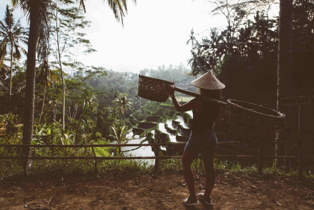 Agriculture woman carrying tools on rice terraces in Ubud Village exploring less visited regions
