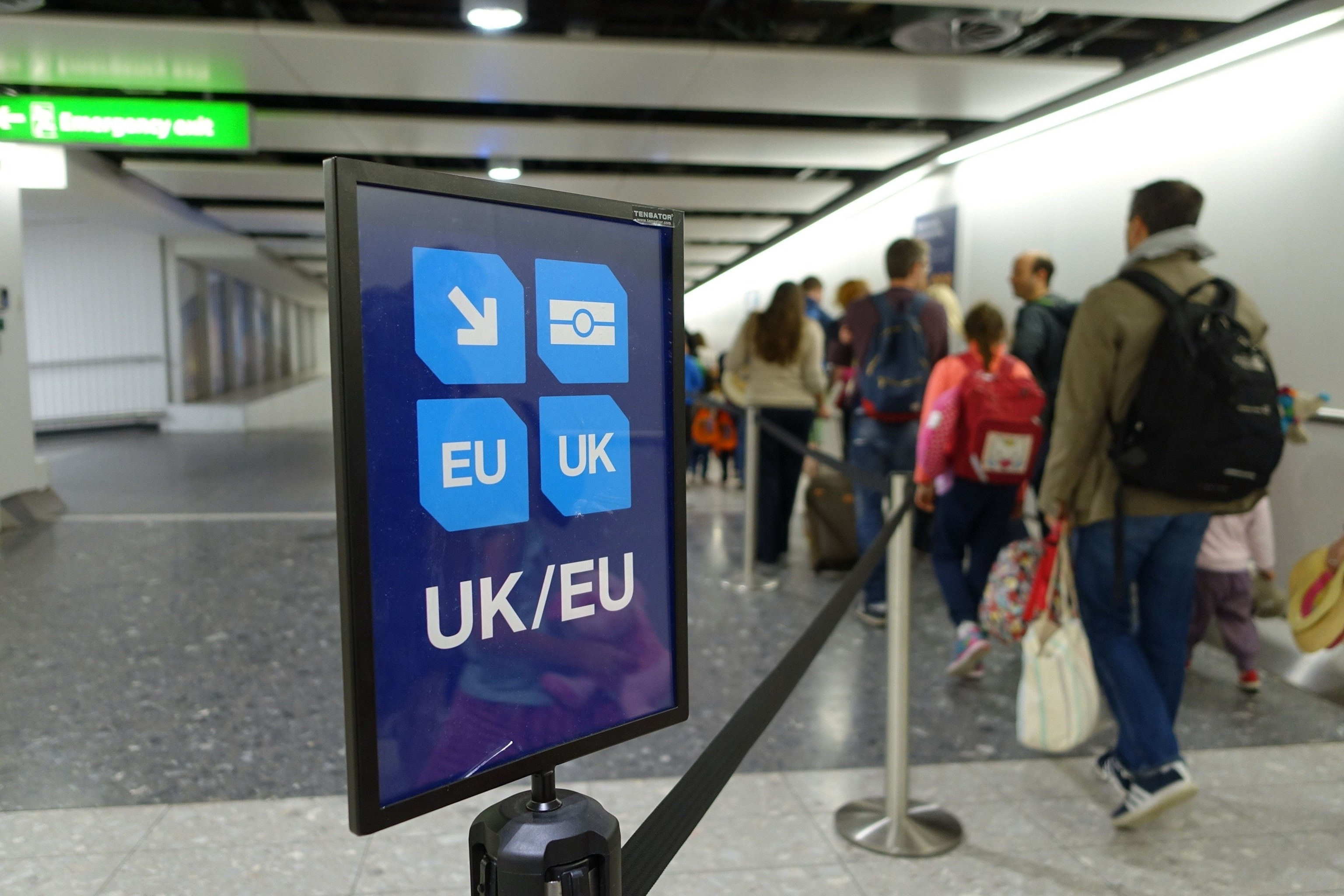 A sign at a British airport directing passengers to UK/EU lanes for passport control, emphasizing the new ETA requirements for entry.