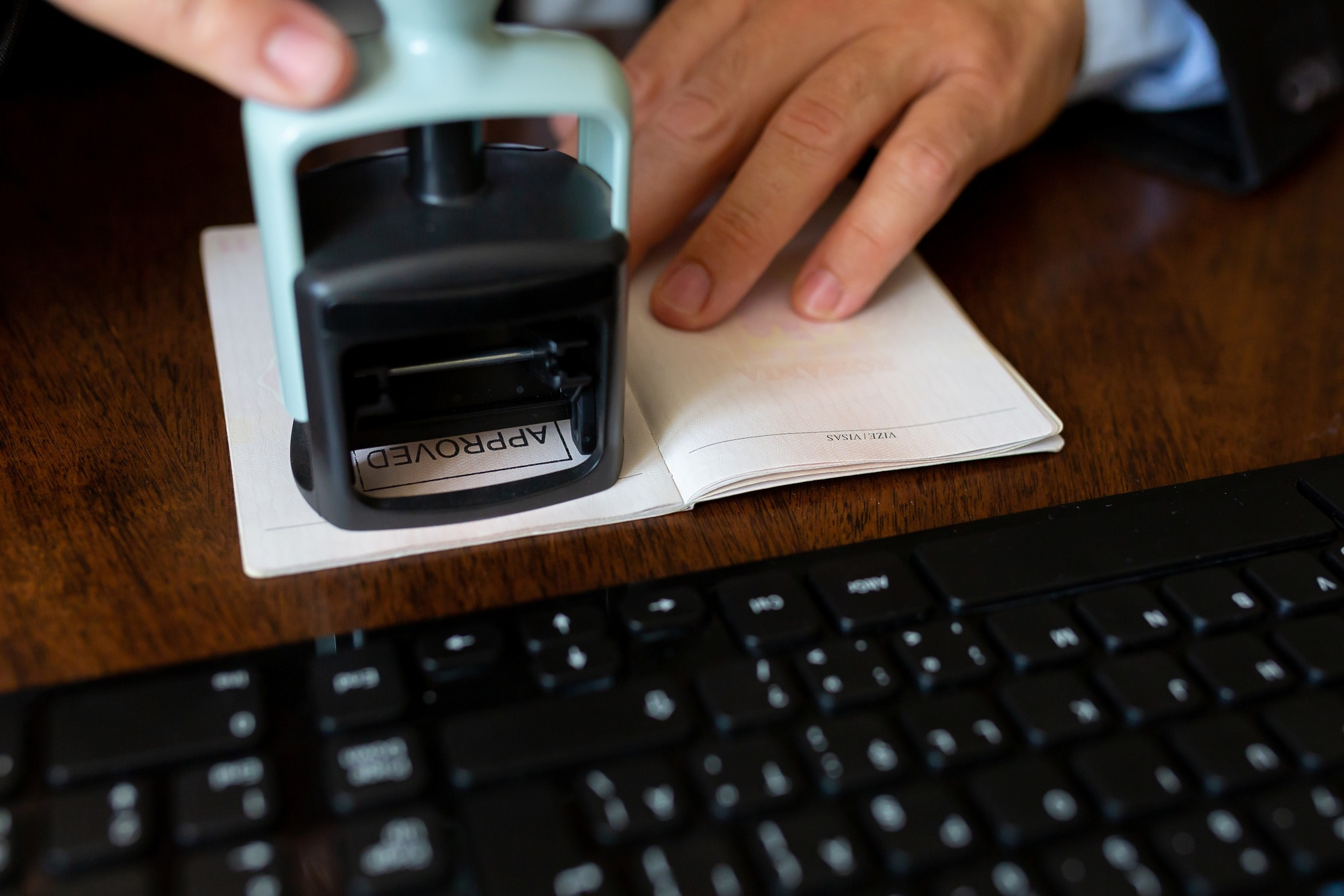 Airport employee stamping a passenger's passport, ensuring all travel documents are in order.
