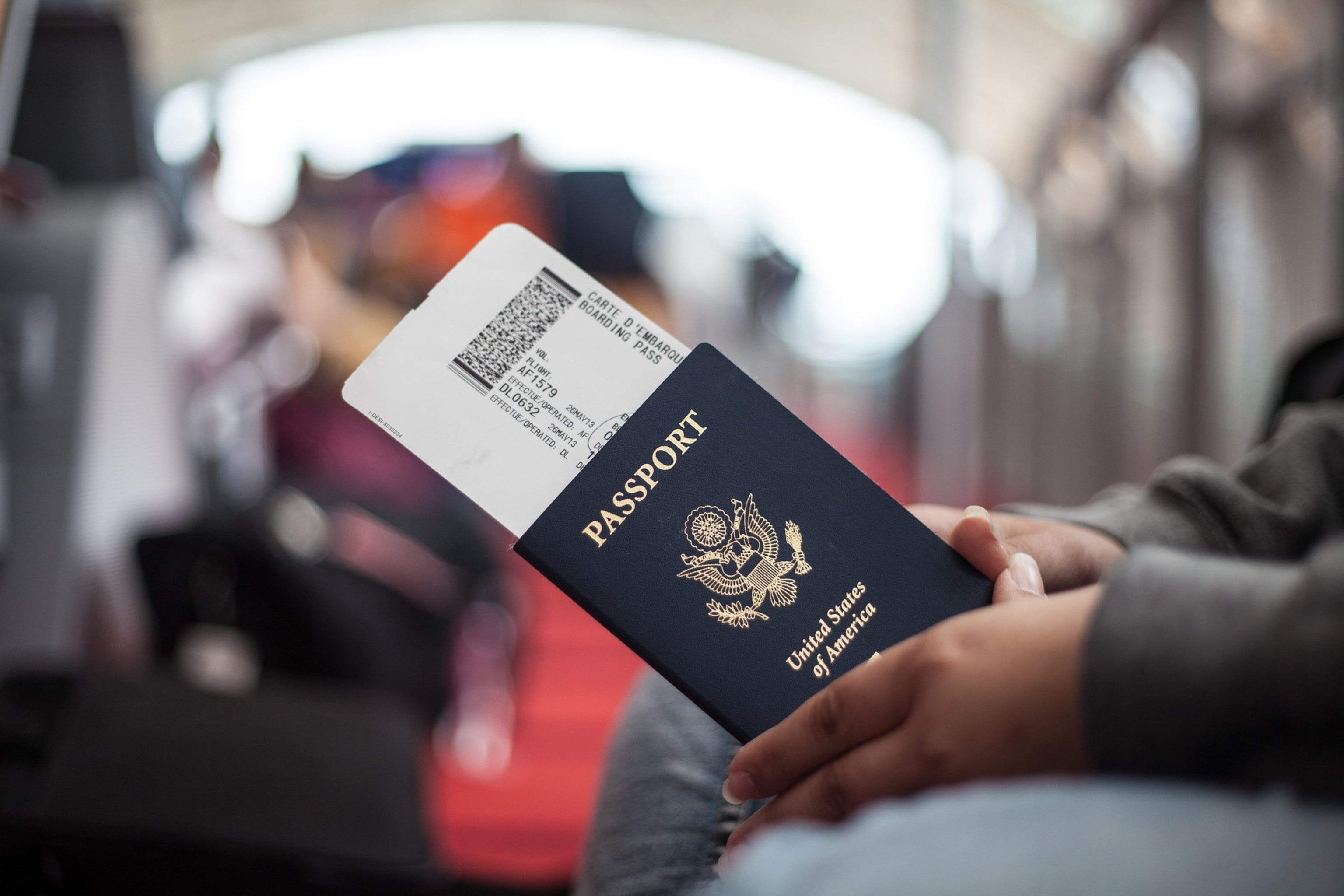 Close-up of a person holding an American passport at an airport, ready for international travel.