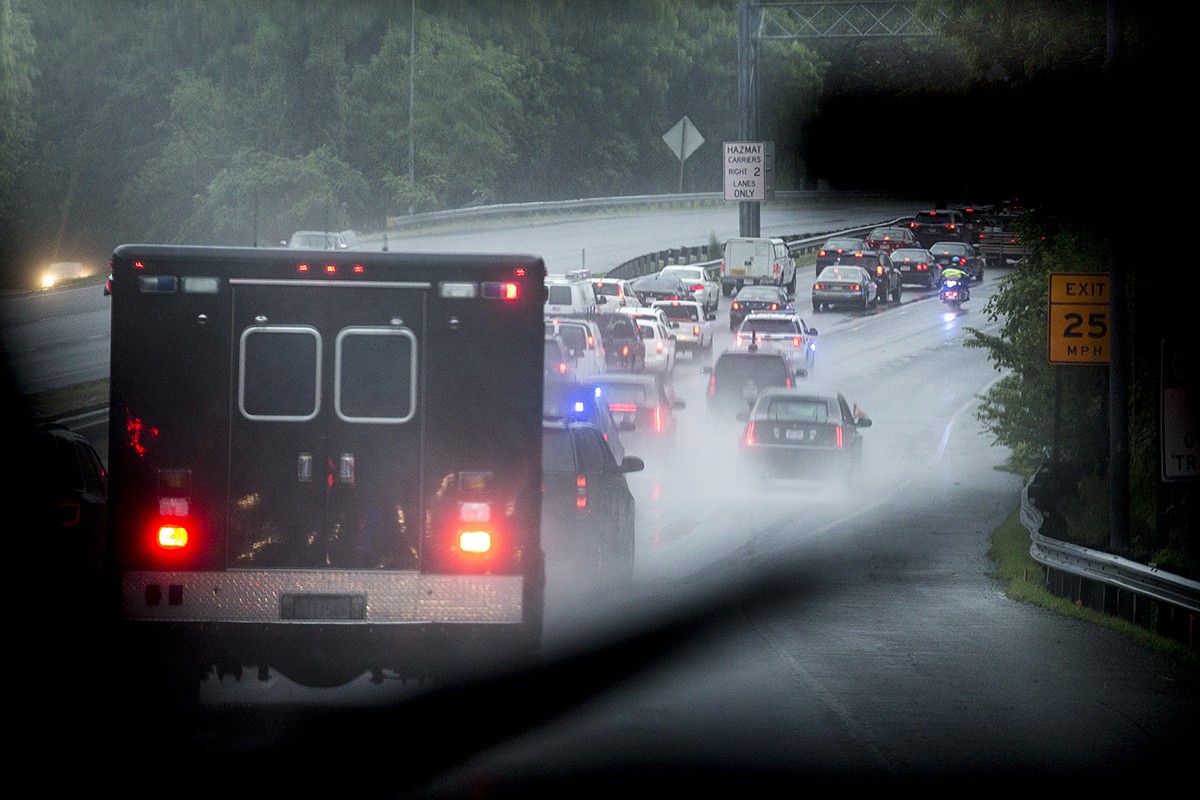 The Presidential Motorcade Makes its way through traffic on a rain-soaked highway
