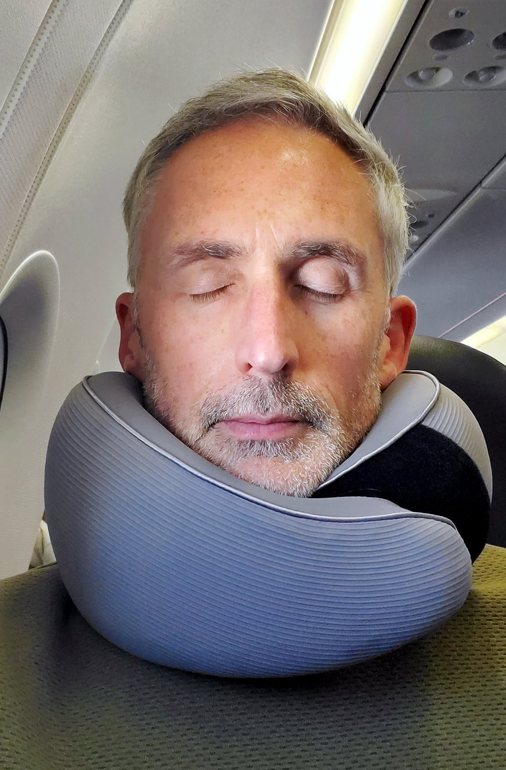 man using AYHome travel pillow on a plane