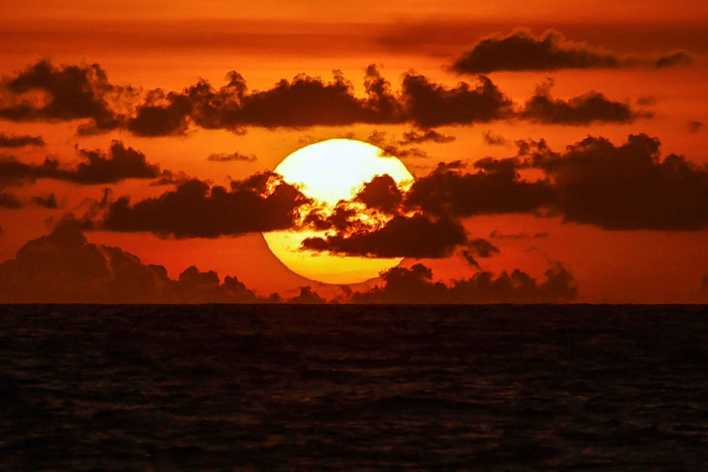 The sun setting over a beach in Bali, creating a picturesque scene.