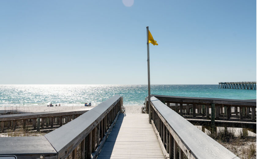 Sign displaying beach flag warning system on Navarre Beach, Florida, indicating water safety conditions