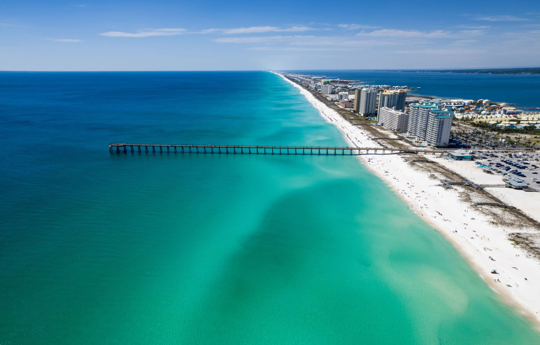 Navarre Beach, Florida, featuring clear turquoise water lapping against the white sandy shore