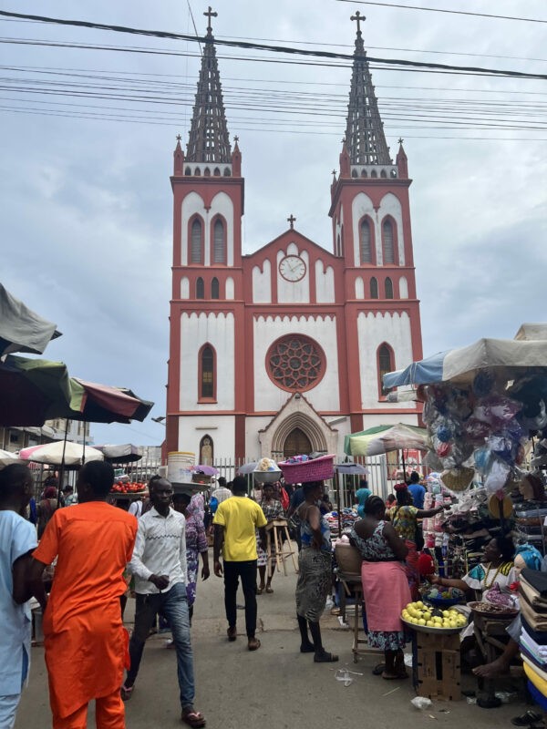 A busy scene at Grand Marché, with vendors selling clothes and other merchandise under colorful umbrellas