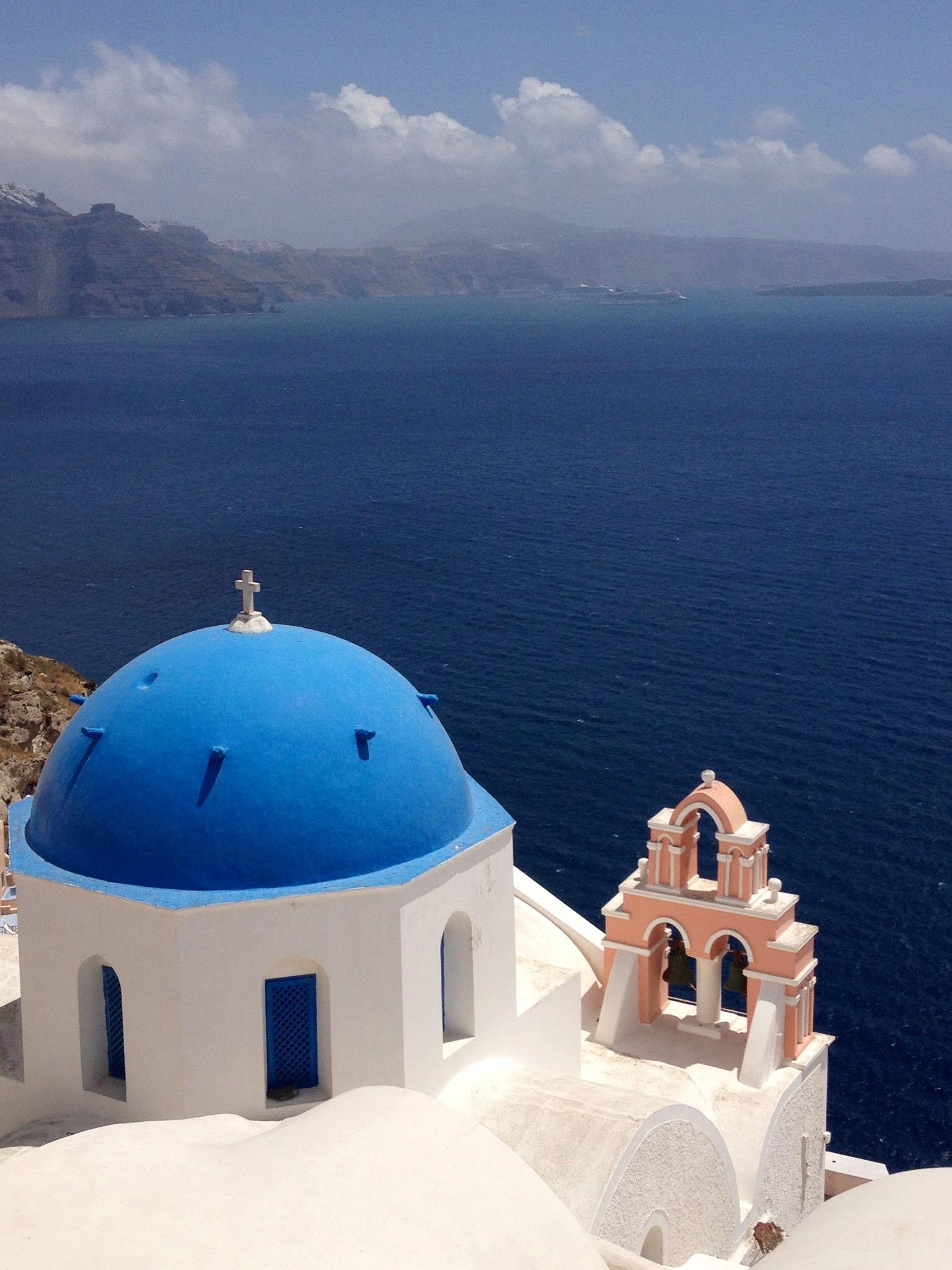 A street in Santorini with colorful bougainvillea flowers and the iconic white buildings