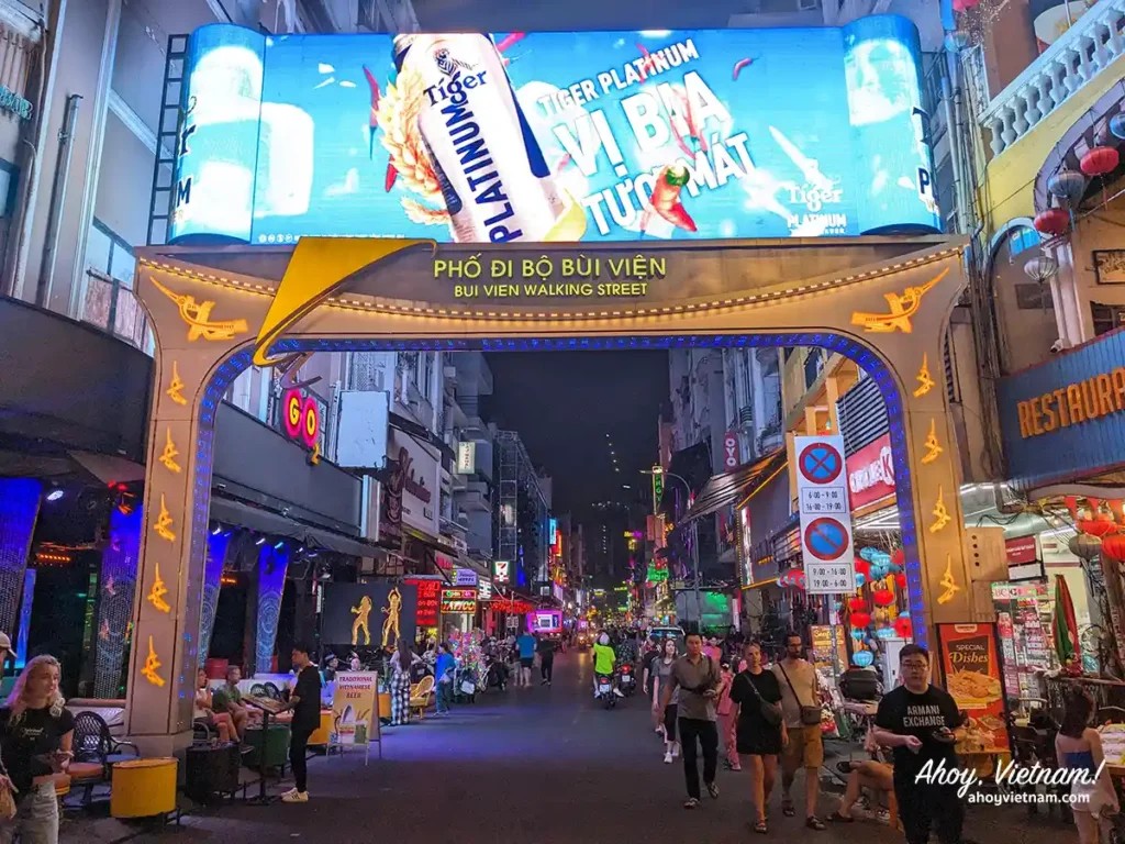 Bui Vien Walking Street entrance with LED sign, showing tourists, partiers, beer signage, and nightlife festivities