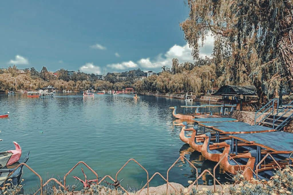 Visitors enjoying a boat ride on the serene Burnham Park Lagoon, surrounded by lush greenery and recreational activities