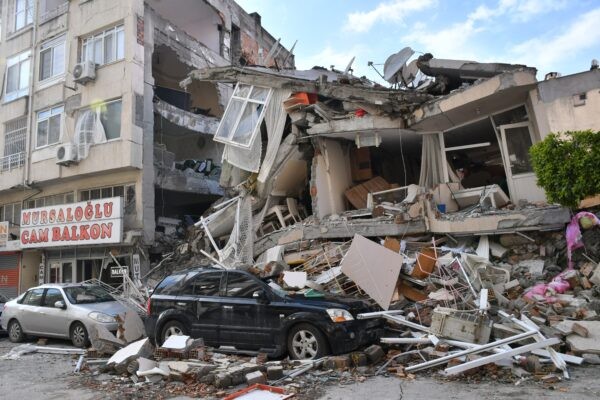 Cars crushed by the aftermath of an earthquake in a city, demonstrating the unpredictable nature of such events