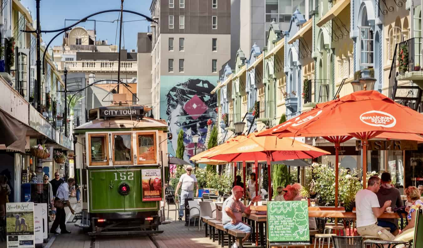 A historic tram gliding through the sunlit streets of Christchurch, New Zealand