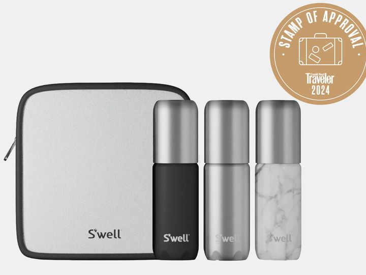 Three S'well travel bottles in black, silver, and marble, with a grey toiletry bag.