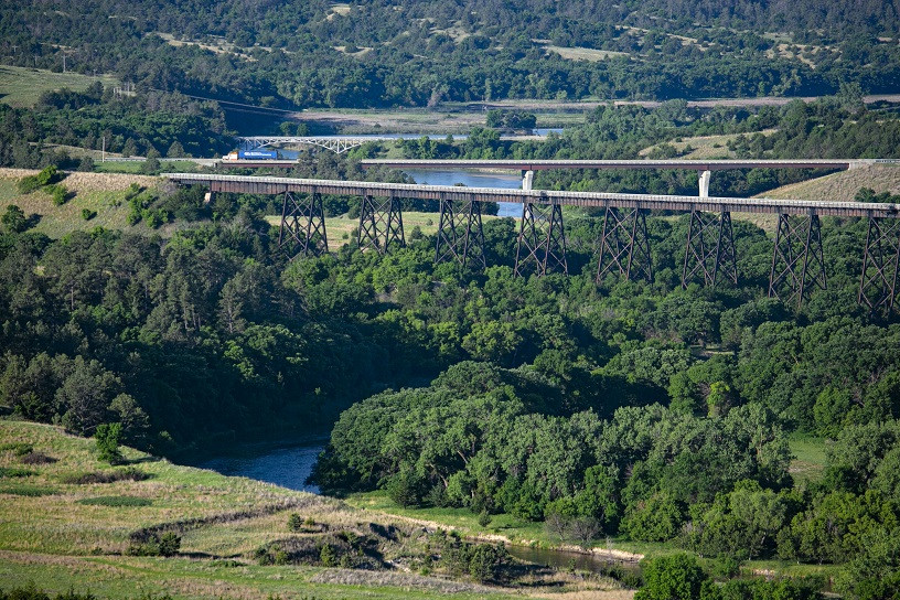 Cowboy Trail Alt Text: A scenic view of Nebraska's Cowboy Trail, showing a gravel path winding through green fields under a vast blue sky, inviting hikers, cyclists, and horseback riders to explore the heart of the Great Plains.