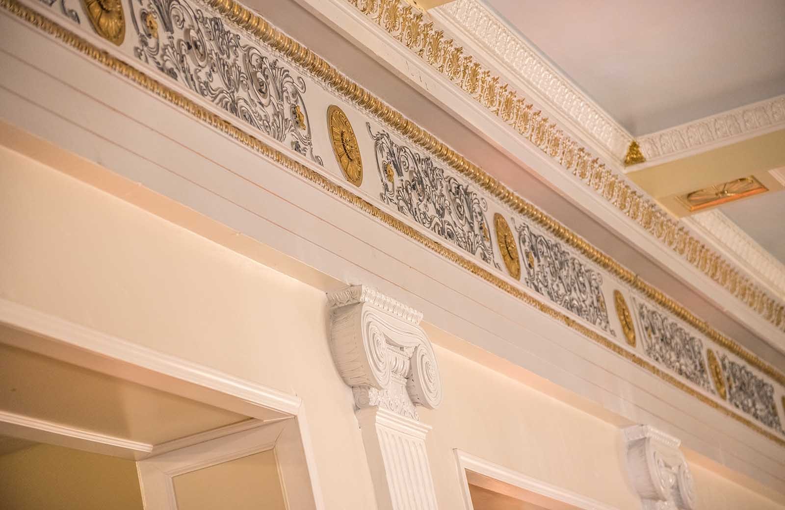 The Crystal Ballroom: Hand-carved pillars and crown molding line the ceiling of the Crystal Ballroom. Accented with golden paint. Architectural details like these, preserved and restored by the Lafayette Grande staff are one of the many ways we stand out from the other banquet facilities.