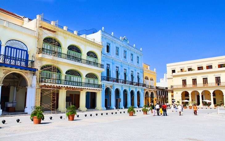 Plaza Vieja in Old Havana, Cuba, featuring colorful colonial architecture and vintage cars