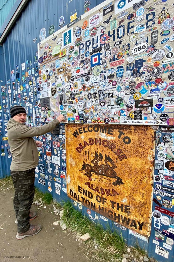 Chris standing next to a Deadhorse welcome sign, offering a glimpse of the town's utilitarian infrastructure