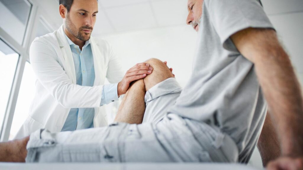 doctor examines elderly mans leg due to radiating knee pain.