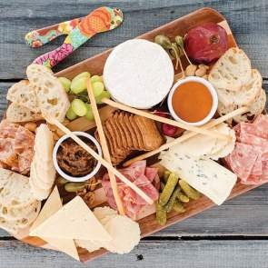 An array of perfectly arranged meats and cheeses on a wooden board