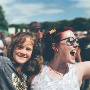 Smiling woman happily holding a child, both enjoying a fun family event