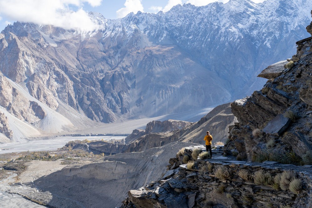 A man walking down a scenic hiking trail overlooking a mountain view