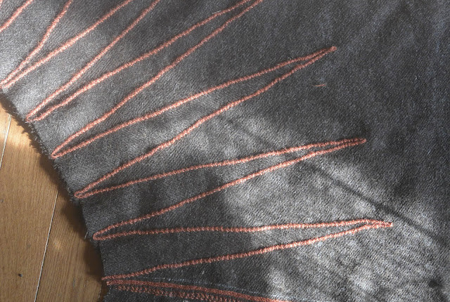 Cross stitch on cloak over 3 strand braid